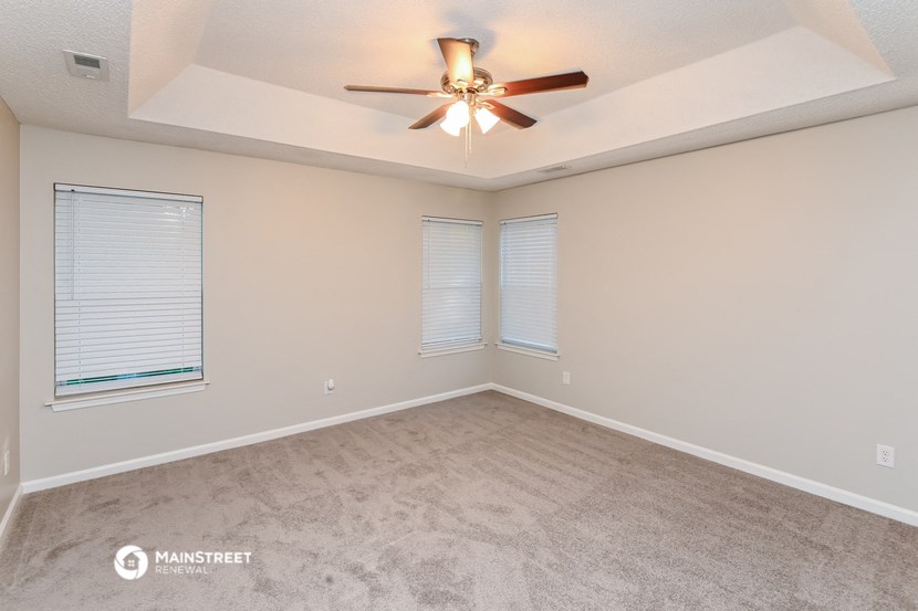 the spacious living room with carpet and ceiling fan
