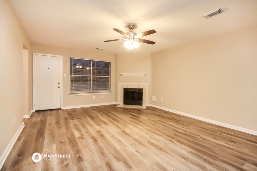 the spacious living room with fireplace and ceiling fan