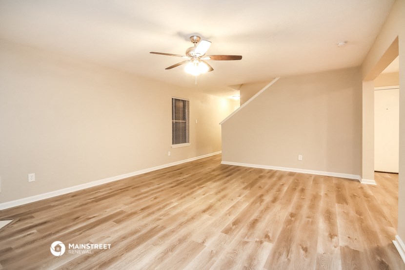 the spacious living room with hardwood floors and a ceiling fan
