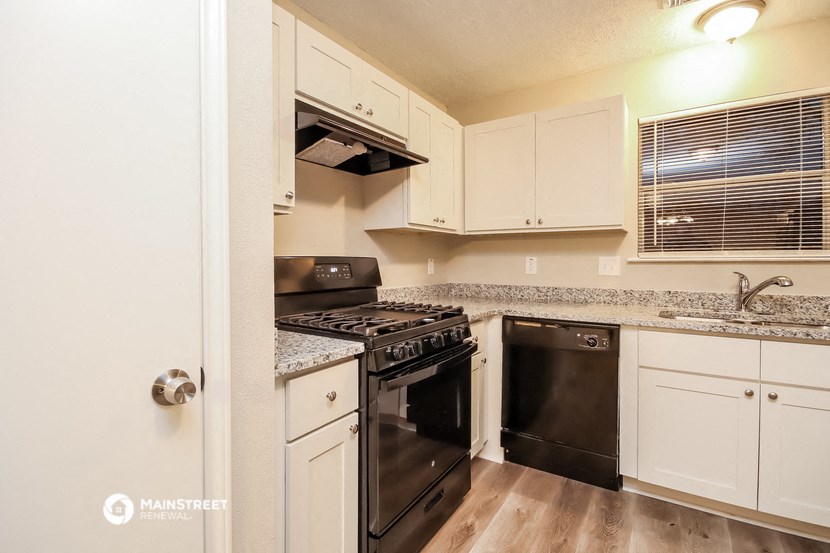 a kitchen with black appliances and white cabinets and granite counter tops