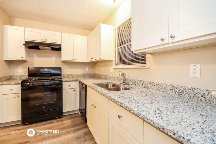 a kitchen with white cabinets and granite counter tops and black appliances