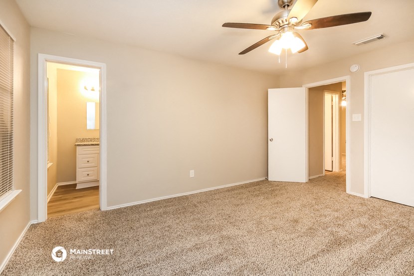 the living room of an apartment with carpet and a ceiling fan