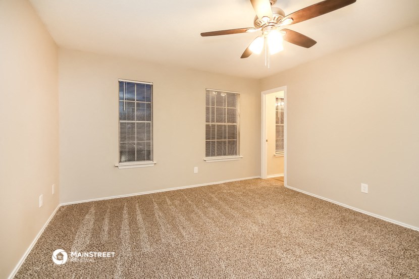 the spacious living room with carpet and a ceiling fan