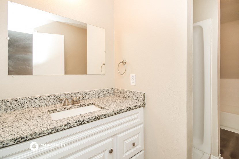 a bathroom with granite counter top and a sink and a mirror