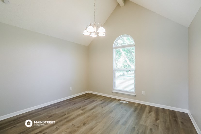 an empty room with hardwood flooring and an arched window