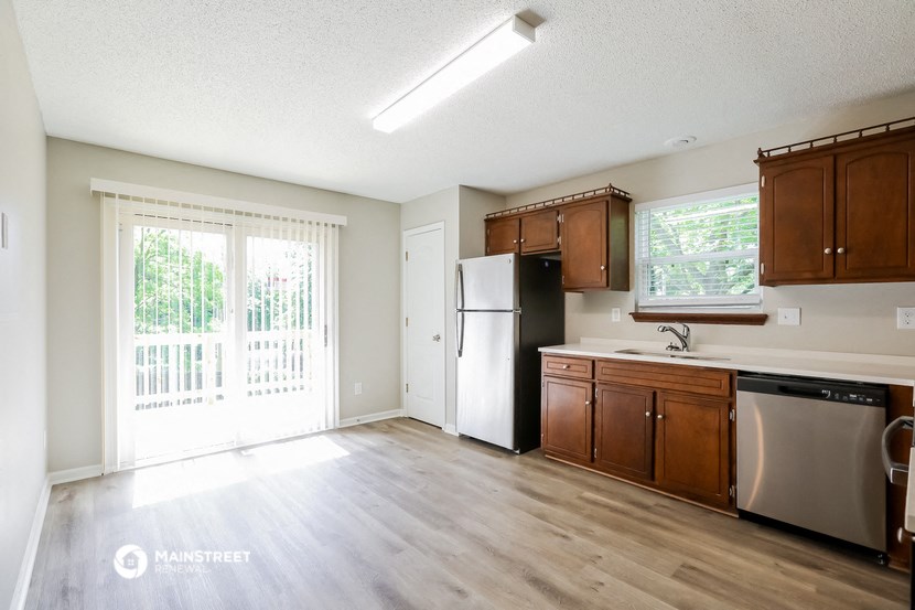 an empty kitchen with wood flooring and a door to a balcony