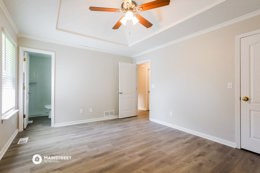 a living room with white walls and a ceiling fan