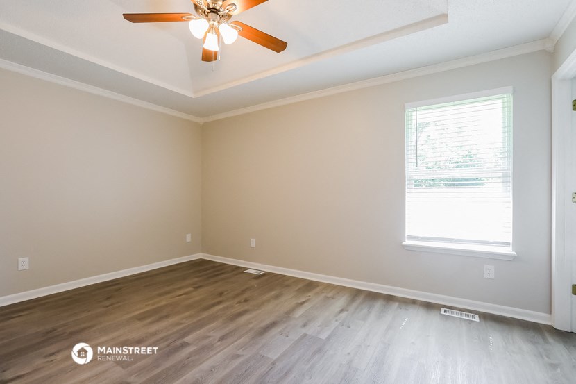 the spacious living room with wood floors and a ceiling fan