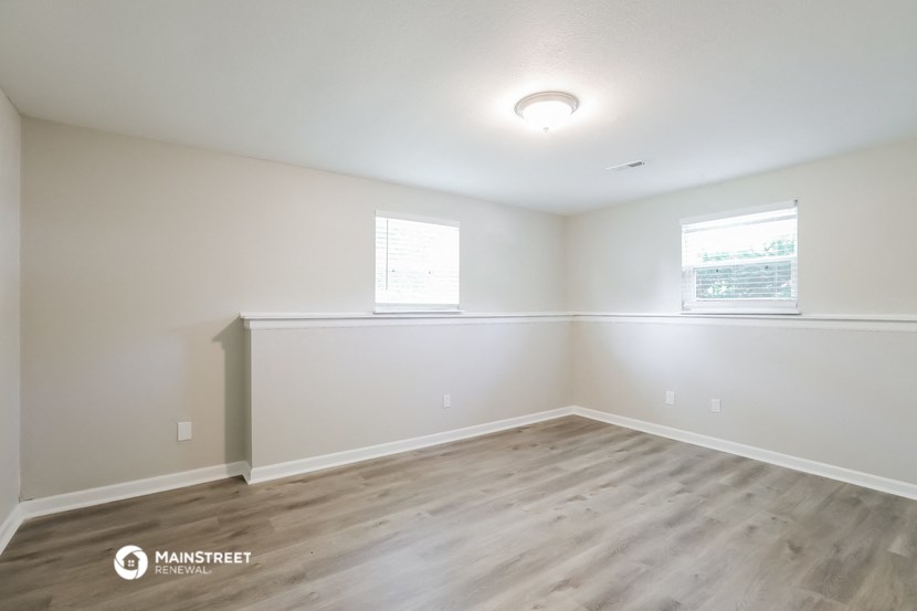 the spacious living room with wood flooring and white walls