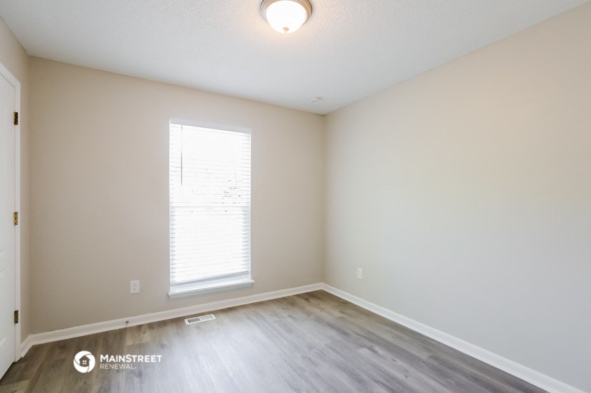 an empty room with wood flooring and a window