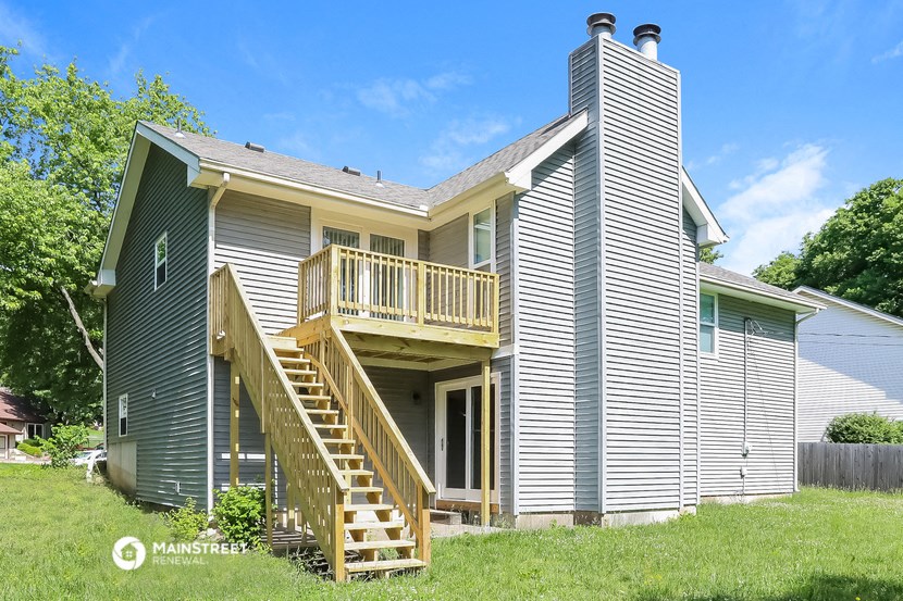the back of a house with a porch and a wooden deck