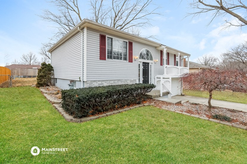a small white house with red shutters and a lawn