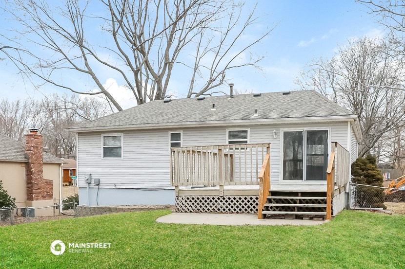 the front of a white house with a deck and a yard