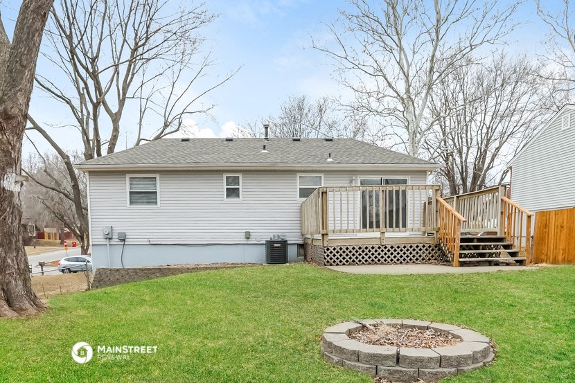a white house with a backyard and a deck with a fire pit