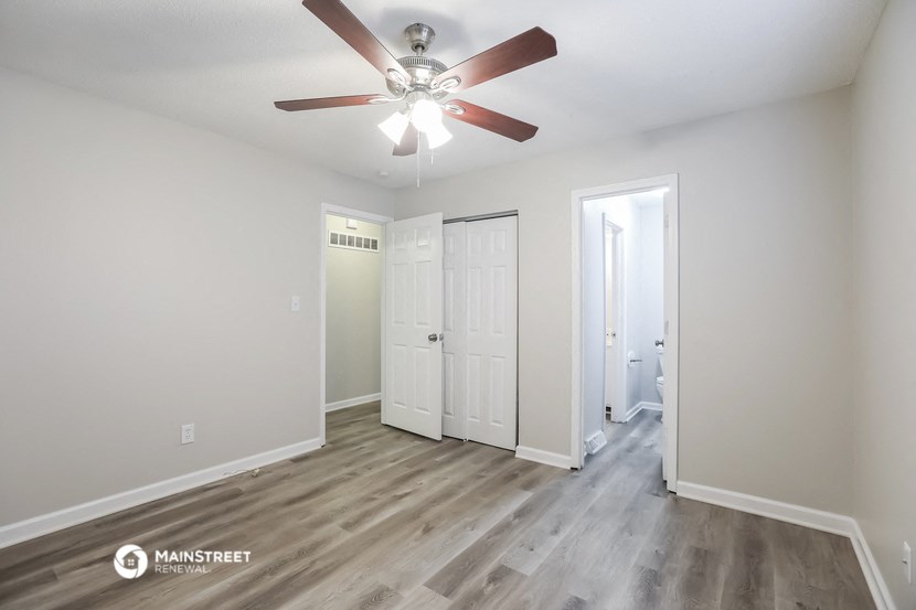 the living room of an apartment with white walls and a ceiling fan
