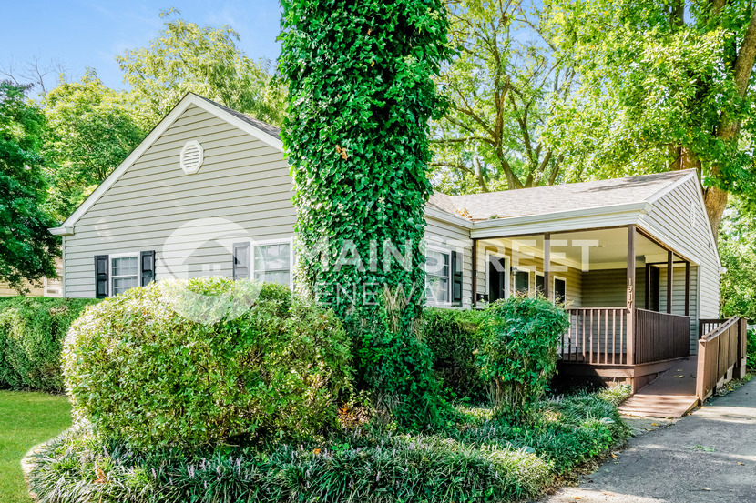 a house with a covered porch and a large tree in front of it