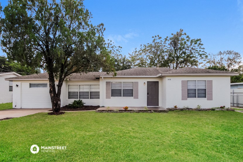a white house with a yard and a tree