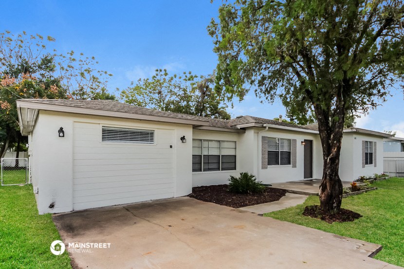 a small white house with a tree in front of it