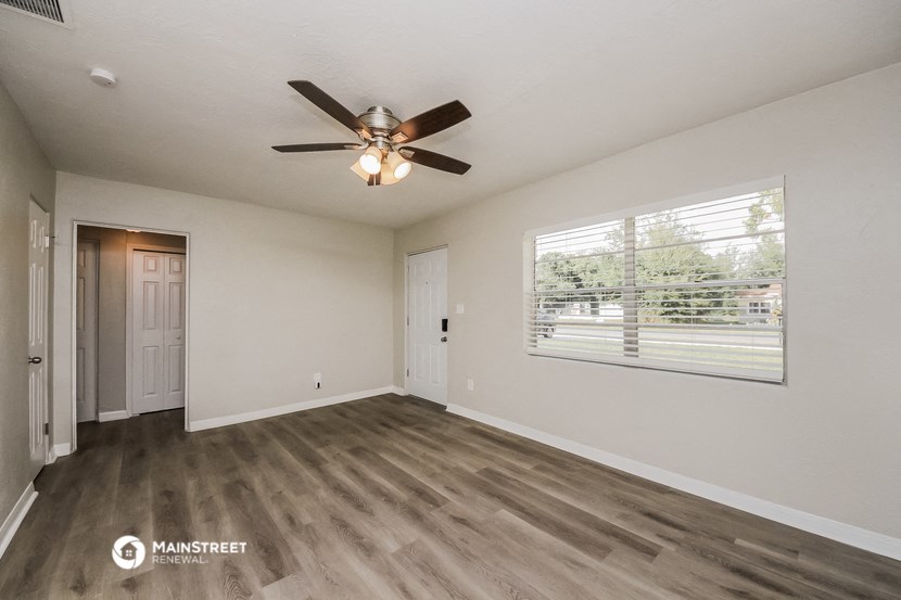 an empty living room with a ceiling fan and a window