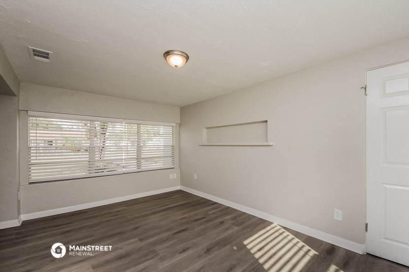 the spacious living room with a large window and wood flooring