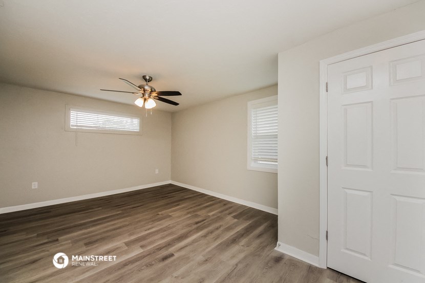 the spacious living room with ceiling fan and wood flooring