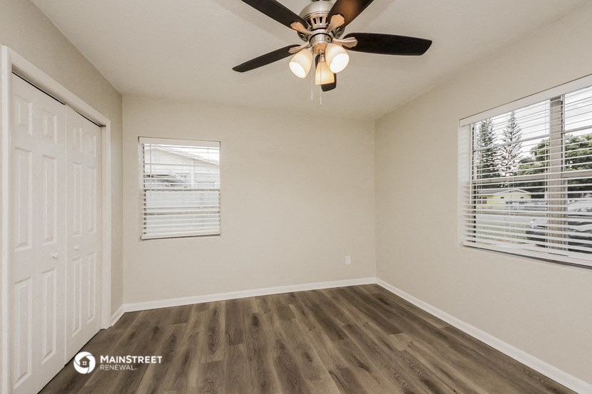 the spacious living room with a ceiling fan and a window