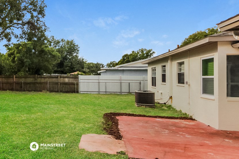 a backyard with a house and a driveway and a fence
