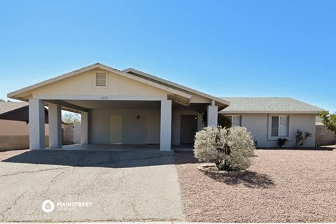 a white house with a gravel driveway and a covered porch