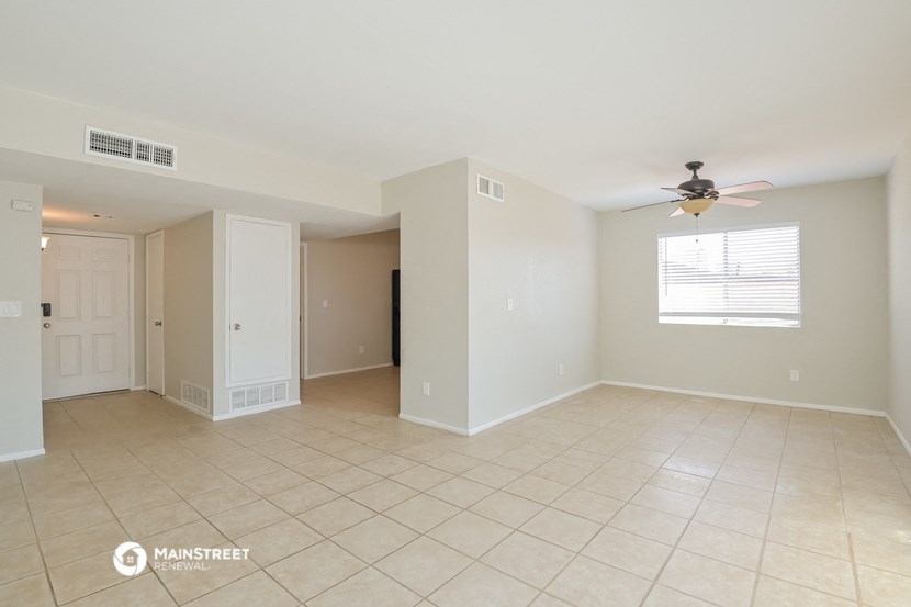 an empty living room with a ceiling fan