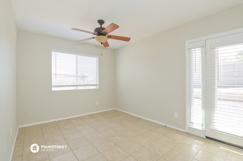 an empty living room with a ceiling fan and a tiled floor