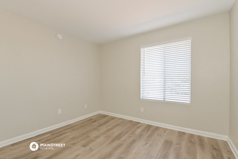 the spacious living room with wood flooring and a window