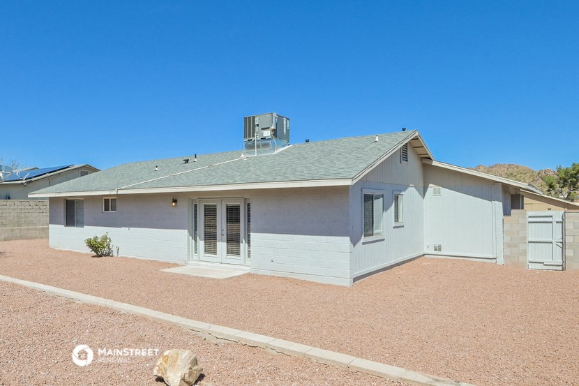 a white house with a gray roof and a gravel yard