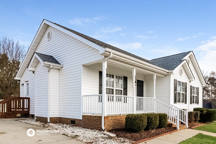 the front of a white house with a porch