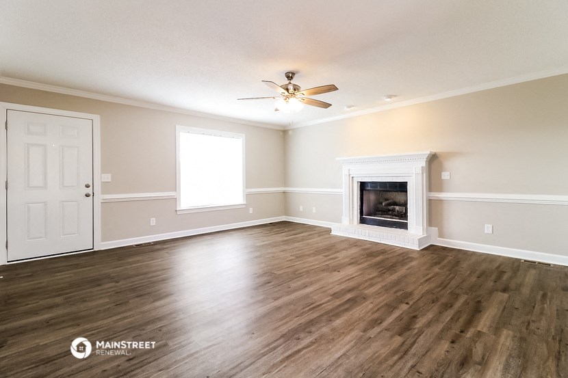an empty living room with a fireplace and a ceiling fan