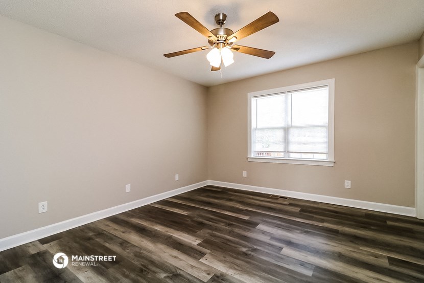an empty living room with a ceiling fan and a window