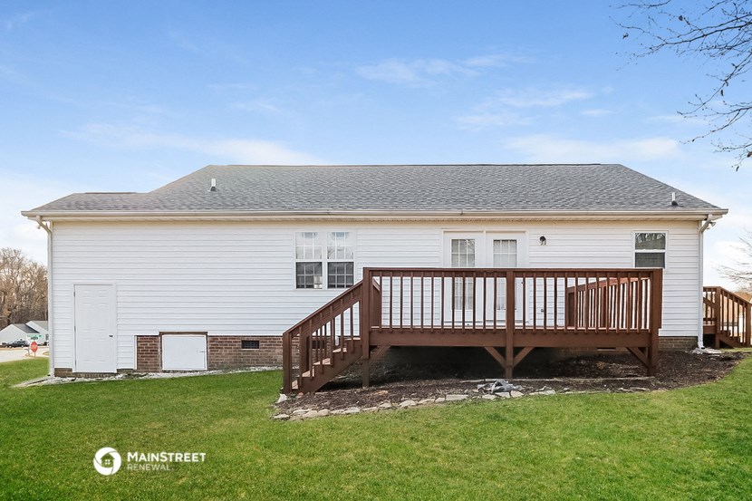 the back of a white house with a wooden deck