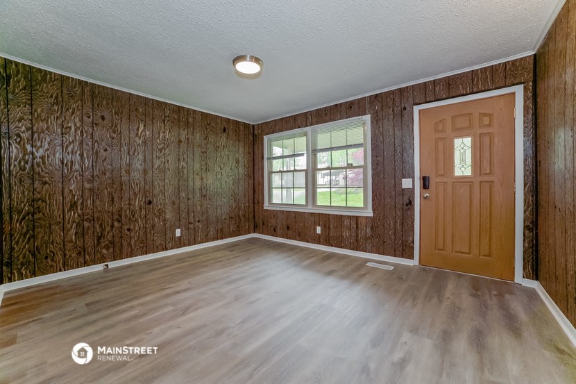 an empty living room with wood paneling and a wooden door