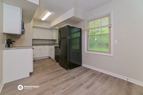the kitchen of an apartment with white cabinets and a black refrigerator