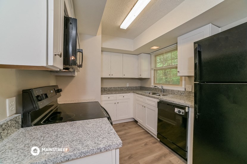 an updated kitchen with black appliances and granite counter tops