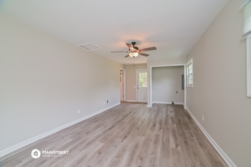 the spacious living room with hardwood floors and a ceiling fan