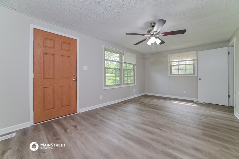 the living room of an empty house with a ceiling fan