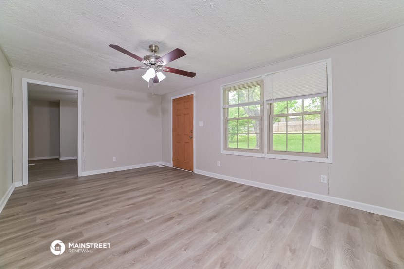 the living room of an empty house with a ceiling fan
