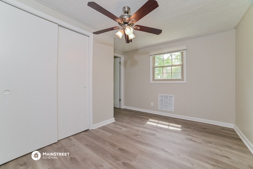 the spacious living room with ceiling fan and closet