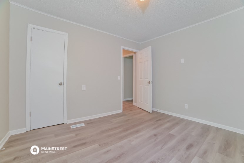 the spacious living room with wood flooring and white walls