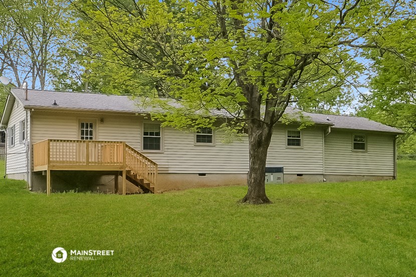 the back of the house with a deck and a tree