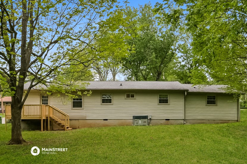 front view of a white house with a deck and trees