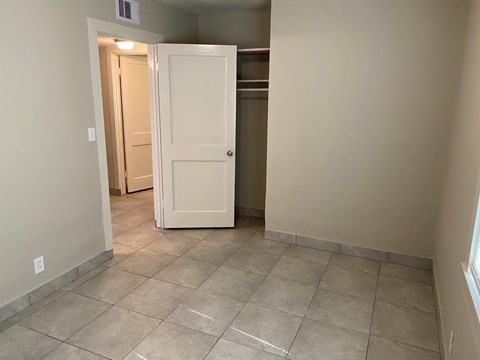 an empty hallway with a white door and tiled floor