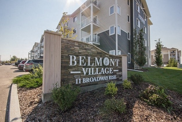 A sign for Belmont Village 11 Broadway Rise in front of a building.