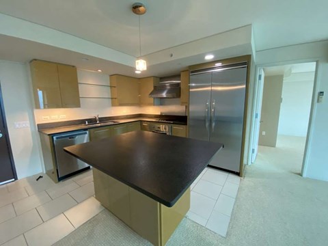 A kitchen with a black counter top and stainless steel appliances.