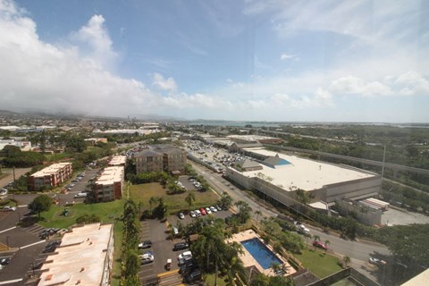 A view of a parking lot with a pool and a building in the distance.